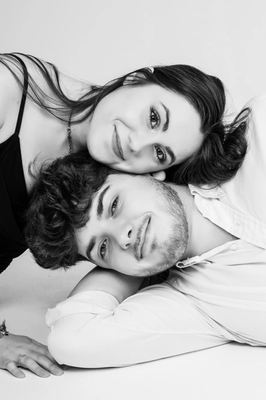 Couple allongé, les visages rapprochés, en noir et blanc.