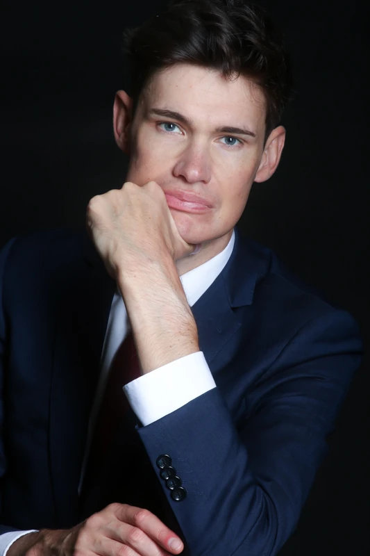 Portrait en studio d’un homme en costume bleu, une main contre le menton — séance Leadership à Lyon.